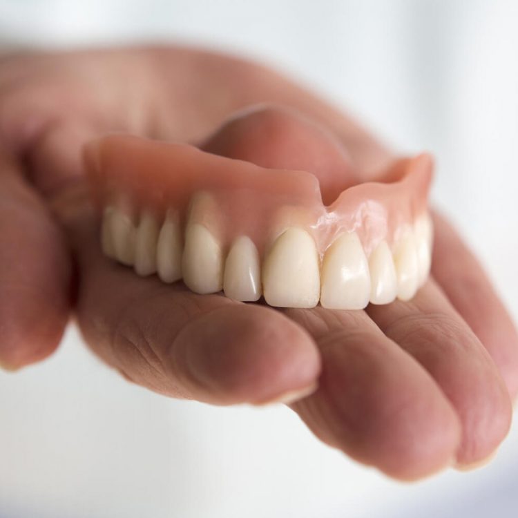 dentist holding Dentures on his hand